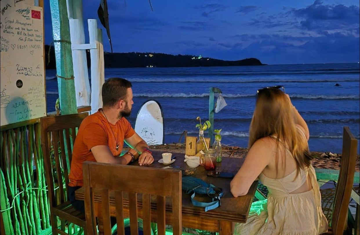 Golden sunset over Unawatuna beach with palm trees and waves